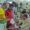 Pakistani men line up as election officials check their ballot papers during voting in Pakistan's general election at a polling station in Lahore on July 25, 2018. - Pakistanis voted July 25 in elections that could propel former World Cup cricketer Imran Khan to power, as security fears intensified with a voting-day blast that killed at least 28 after a campaign marred by claims of military interference. (Photo by WAKIL KOHSAR / AFP)